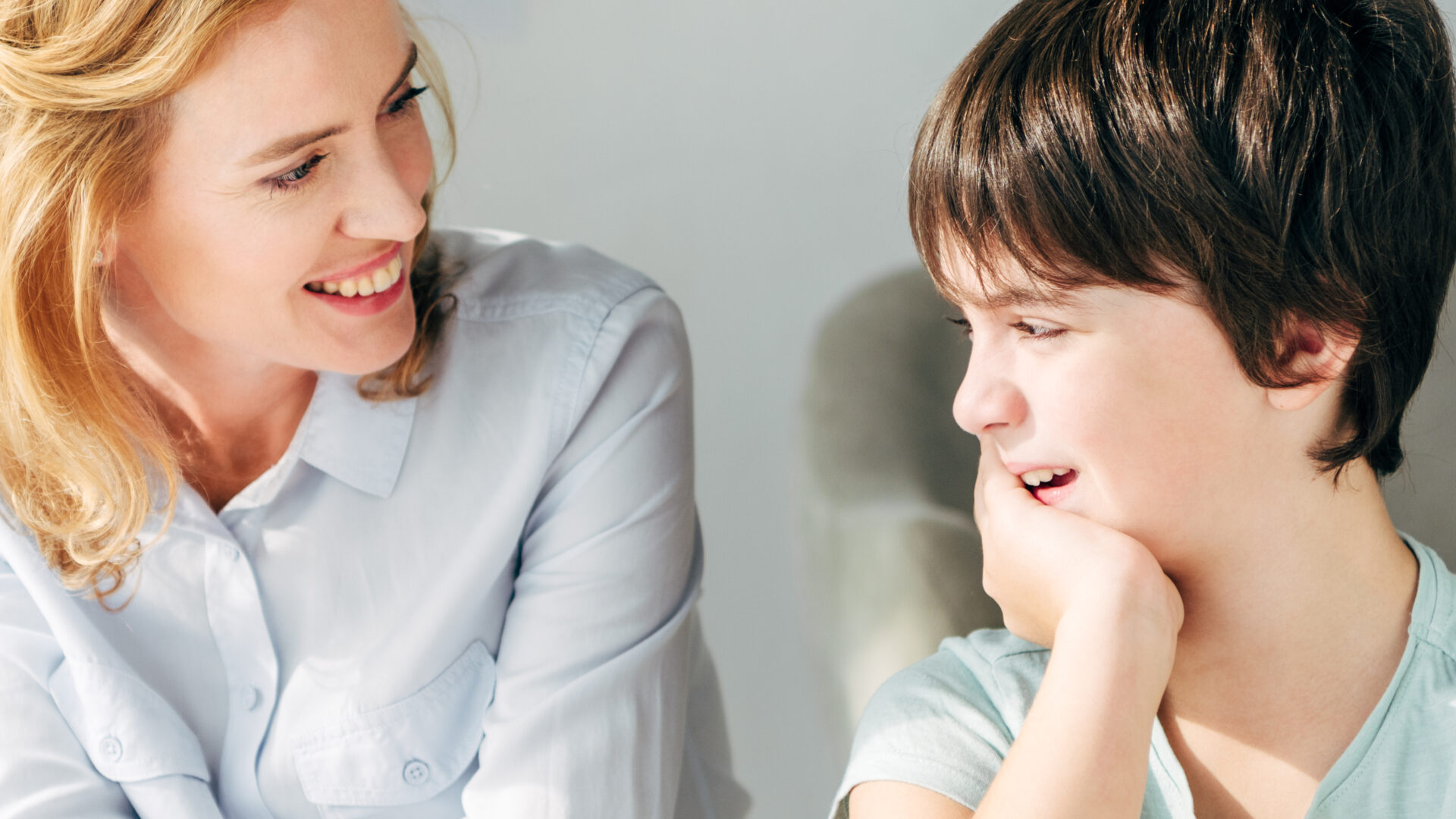 panoramic shot of smiling child psychologist looking at kid with dyslexia